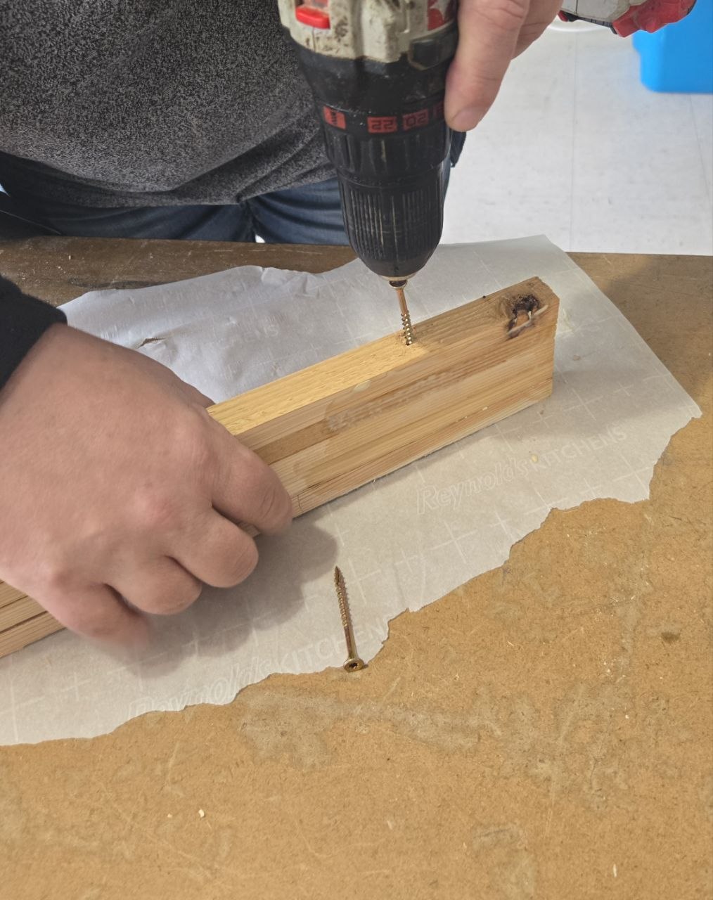 Close-up of drilling and screwing the base of the cedar fan trellis together