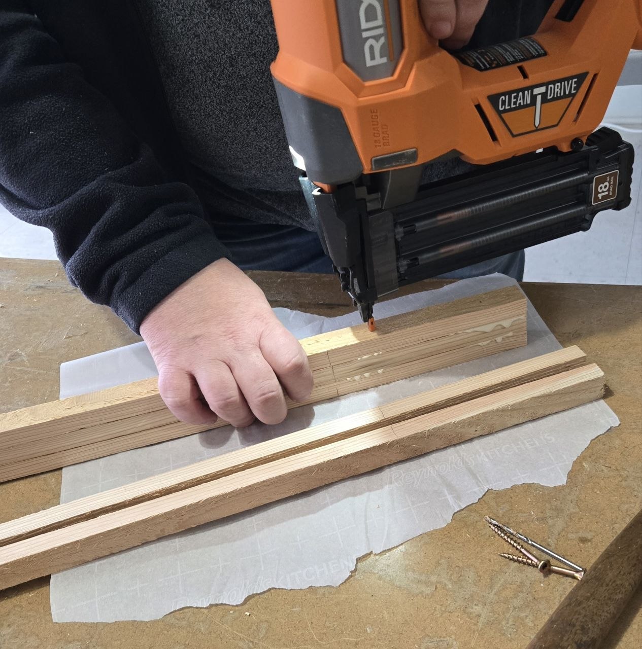 Pin nailing the cedar fence picket fan pieces together at the base of the trellis