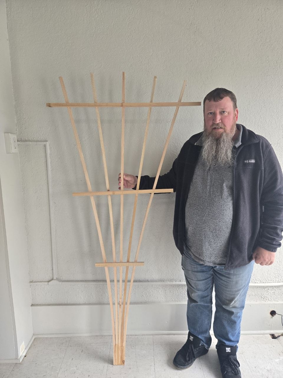Finished simple cedar fan trellis held up indoors before being installed for the raspberry bush