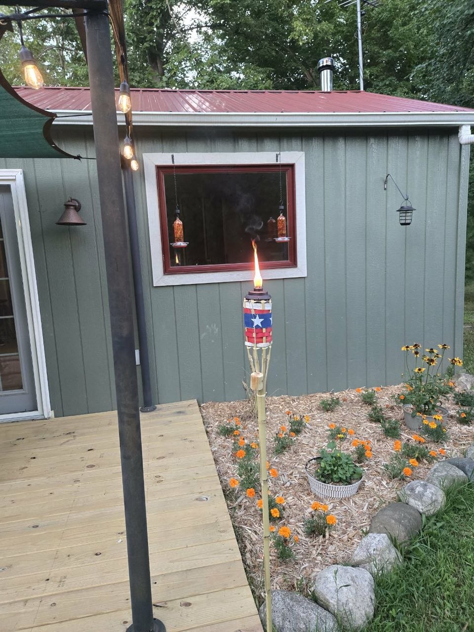 Tiki torch and deck-side flower bed detail added during the slower dog days of summer