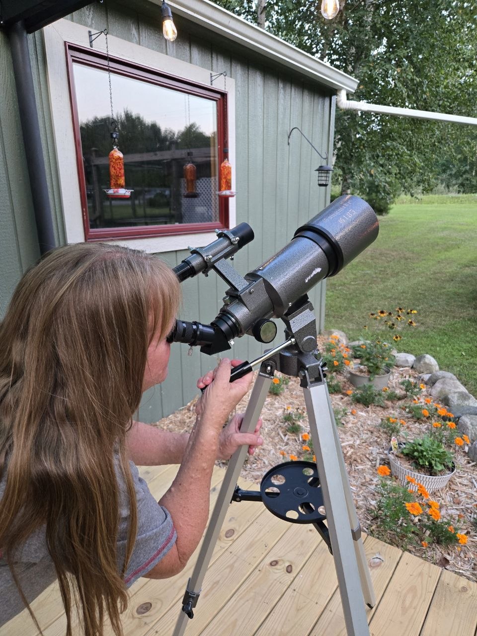 Vanessa using a telescope on the deck during the slower August nights at the cabin