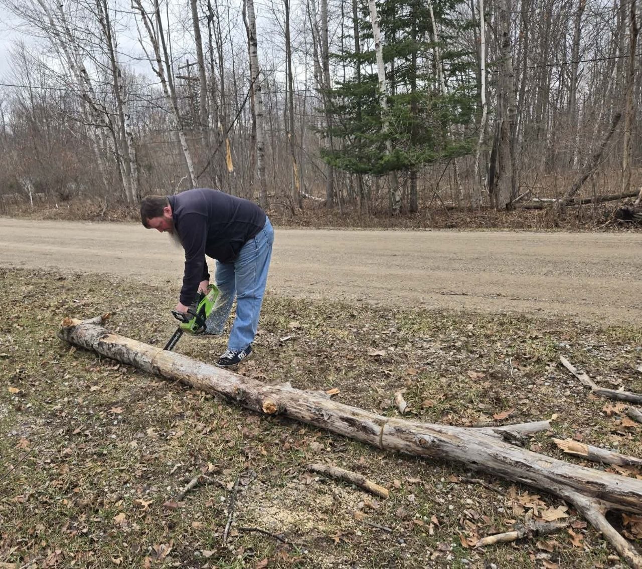 Jeff cutting up a fallen branch near the road during the first spring cleanup trip of 2026