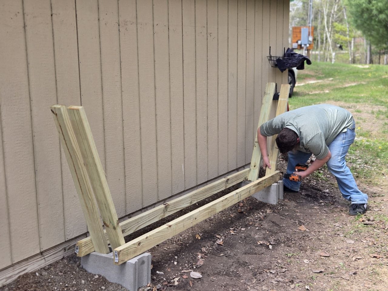 Building the new firewood stand along the cabin wall during the 2026 cabin opening trip