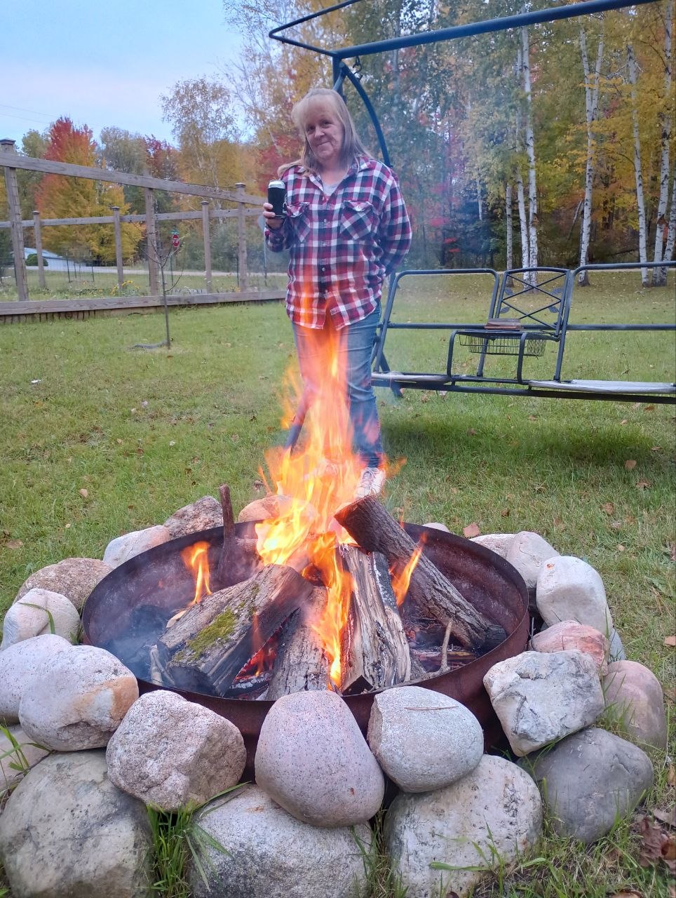 Vanessa by a fall bonfire at the cabin near the fire ring and swing