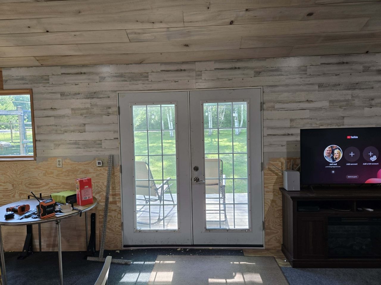 Cabin wall progress with plywood lower section and decorative upper paneling after a frustrating final workday in June 2026